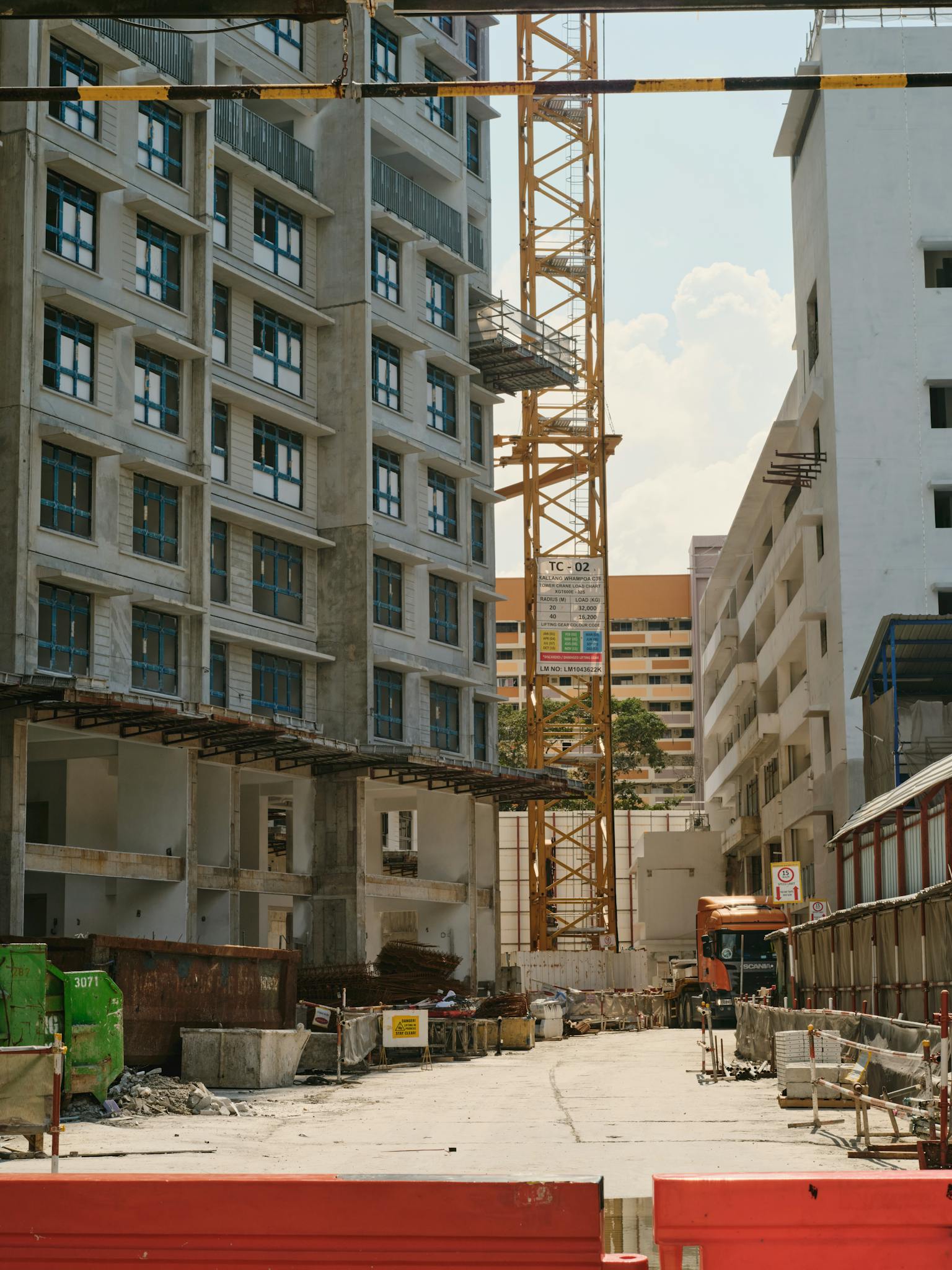 A bustling urban construction site with a tower crane and surrounding buildings under a clear sky.