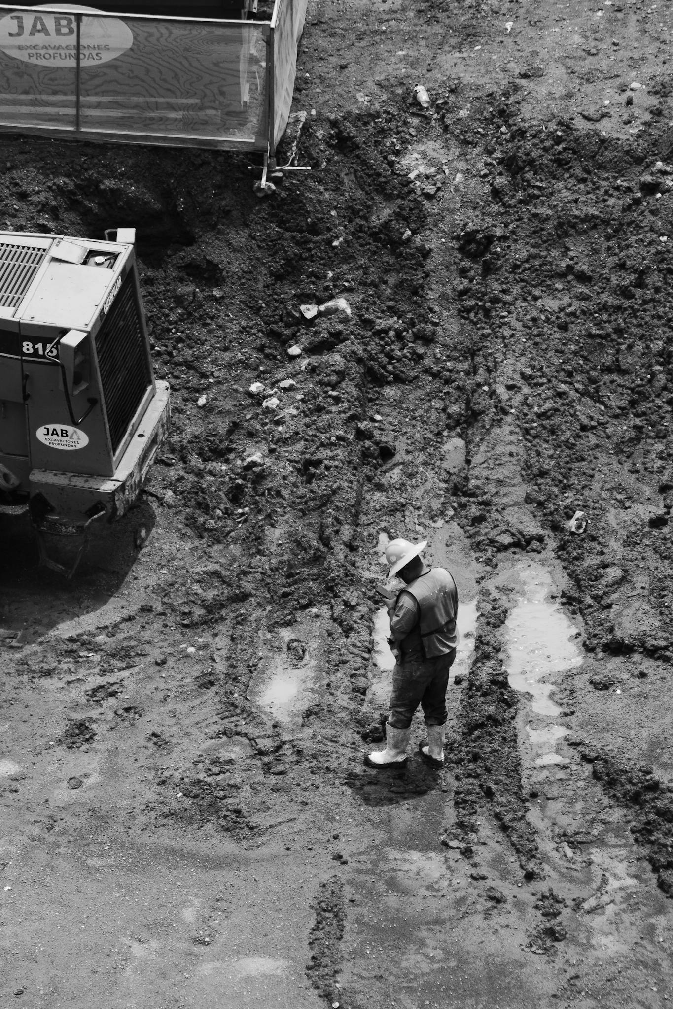Black and white image of a construction worker on a muddy site in Mexico City from above.